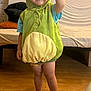 Zahïm participe au concours pour gagner de l'argent avec cette photo : child, toddler, costume, green, dinosaur, smile, barefoot, wooden_floor, indoor, couch, cushion, person, clothing, happy, shorts, headwear, standing, room, home, playful
