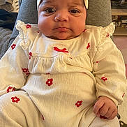 Zoya a rejoint le concours — aidez-le/la à gagner de superbes lots ! baby, infant, child, face, headband, clothing, white_outfit, red_flowers, pout, hand, sitting, indoors, soft_lighting, cute, portrait, young_child, cozy, expression, human, person