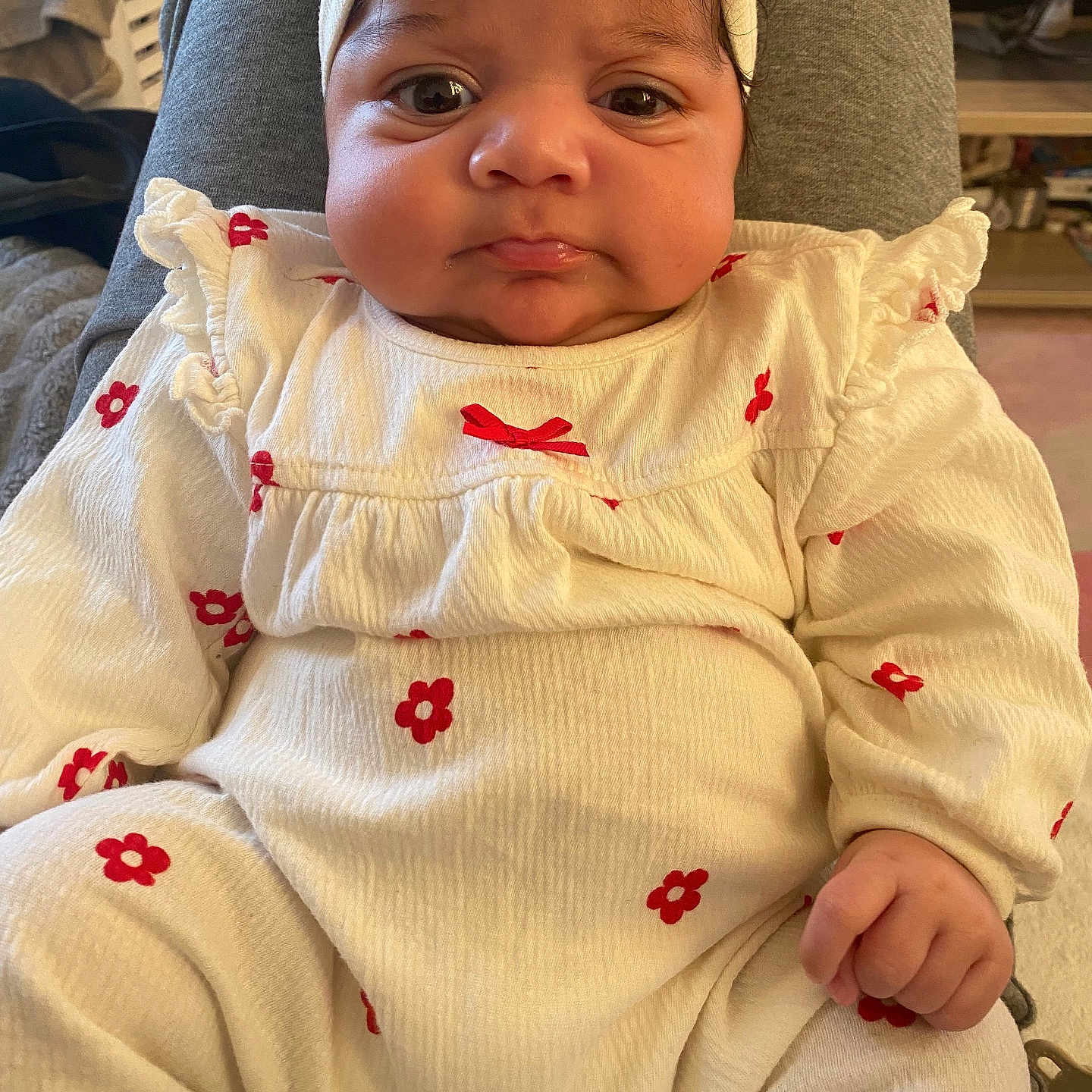 Zoya a rejoint le concours — aidez-le/la à gagner de superbes lots ! baby, child, clothing, cozy, cute, expression, face, hand, headband, human, indoors, infant, person, portrait, pout, red_flowers, sitting, soft_lighting, white_outfit, young_child