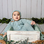 Eesa Abbas joined the competition — help win amazing prizes! baby, blue, buttoned_sweater, child, cozy, crate, cute, expression, floor, greenery, hat, indoors, infant, knitwear, person, plant, portrait, seated, wooden_box, young