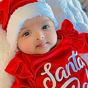 Aveera joined the competition — help win amazing prizes! baby, child, infant, santa_hat, red_clothing, festive, holiday, cute, smile, face, portrait, lying_down, blanket, soft_texture, indoors, warm, comfortable, young_child, christmas, holiday_season