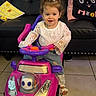 Adhara is registered to the contest to win money with this photo: black_couch, cat_pillow, child, colorful_toy, cute, floor_tiles, footwear, hair_bow, happy, home, indoor, living_room, person, playful, sitting, smiling, toddler, toy_car, white_lace_top, young_child