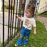 Adhara is registered to the contest to win money with this photo: casual, child, clothing, curious, daylight, fence, girl, grass, hair, house, nature, outdoor, pants, person, pony_tail, shirt, sidewalk, standing, toddler, urban