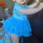 Adhara joined the competition — help win amazing prizes! toddler, child, blue_dress, boots, couch, indoor, furniture, curly_hair, earrings, watch, room, pillow, table, flowers, light, person, standing, holding, cute, expression