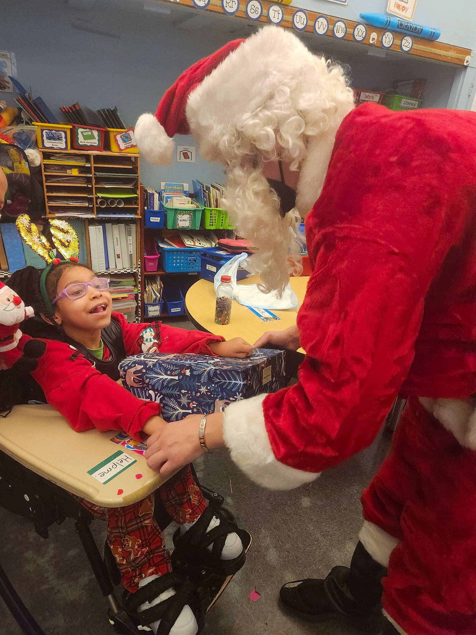 Genevieve is registered to the contest to win money with this photo: box, carmine, christmas, christmas_eve, costume, event, fictional_character, fun, fur, holiday, leisure, mascot, person, retail, santa_claus, service, shelf, shopping, stuffed_toy, table