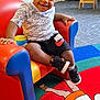 Antonio is registered to the contest to win money with this photo: toddler, child, smiling, indoor, armchair, colorful, nike, sneakers, carpet, playroom, furniture, child_furniture, happy, person, shorts, tshirt, play_area, floor, toy, room
