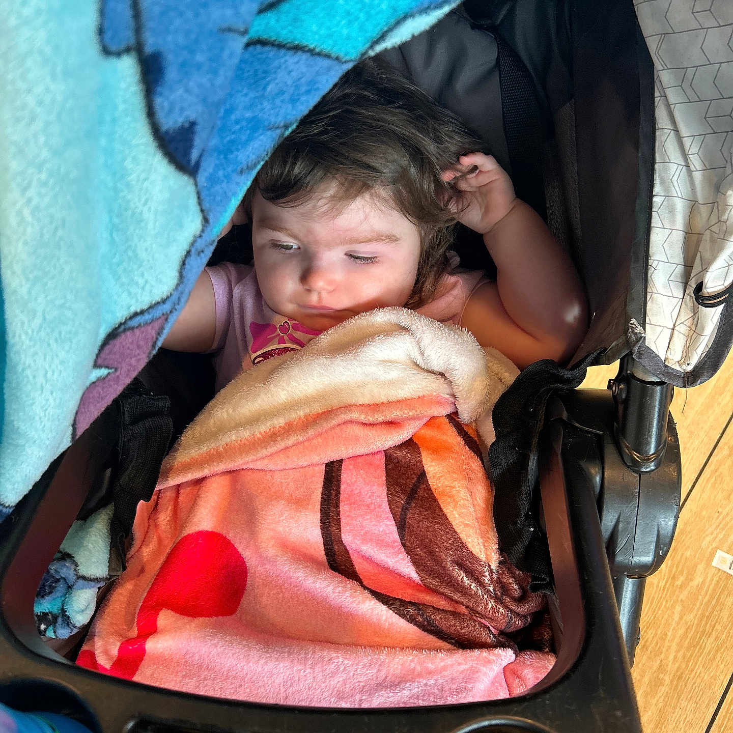 Sadie is registered to the contest to win money with this photo: toddler, child, blanket, stroller, goldfish_crackers, sippy_cup, indoor, cozy, sleepy, colorful, food, snuggled, seat, wood_floor, patterned_blanket, baby, young_child, resting, cute, casual