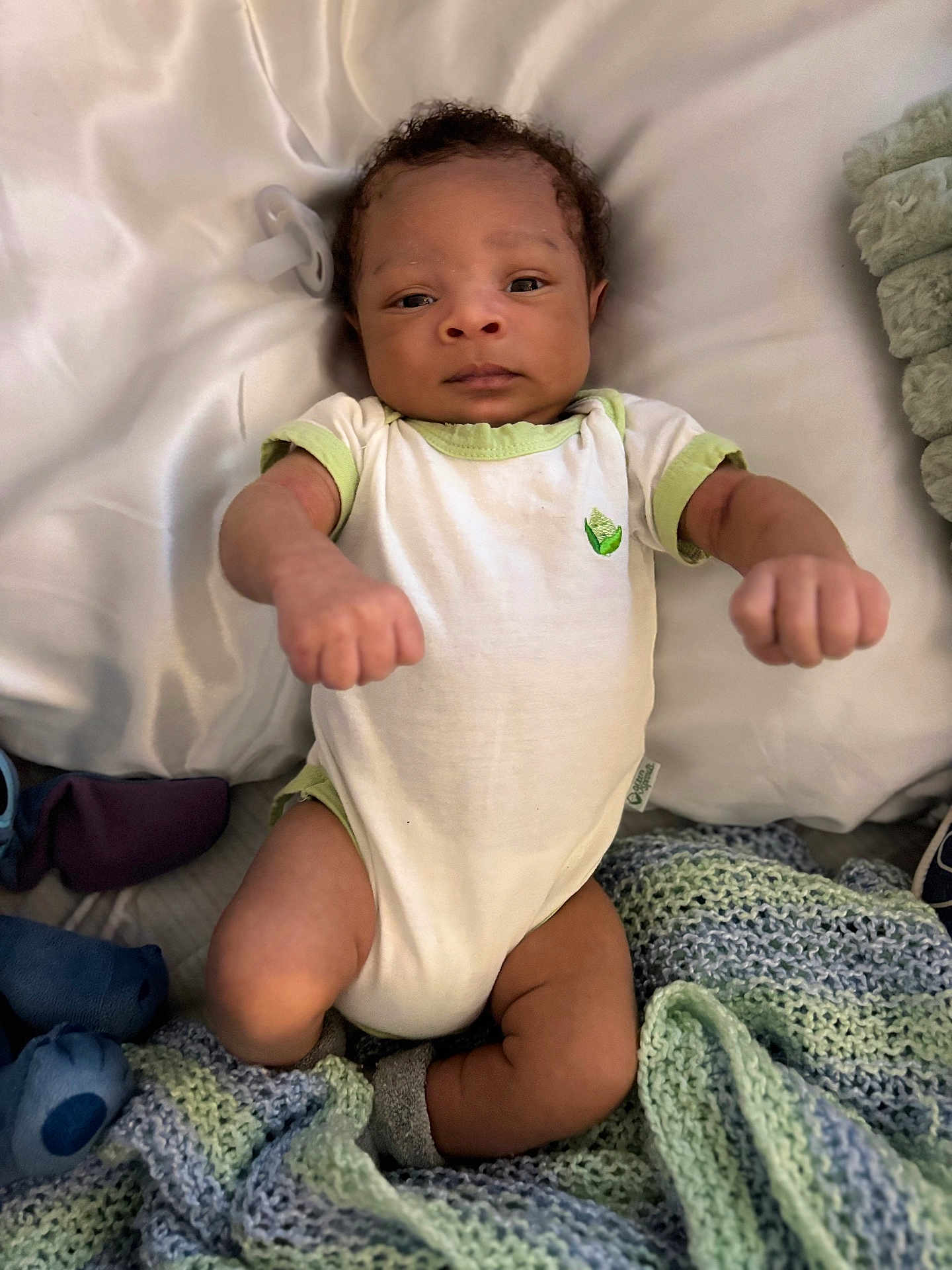 Adam is registered to the contest to win money with this photo: baby, infant, onesie, blanket, knitted_blanket, pacifier, fist, lying_down, soft_texture, baby_clothes, newborn, cute, child, person, indoors, portrait, sleeping_area, resting, infant_boy, cozy