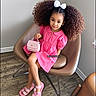 Morgan joined the competition — help win amazing prizes! child, girl, portrait, sitting, pink_dress, curly_hair, hair_bow, handbag, sandals, fashion, smiling, indoors, chair, furniture, wood_floor, home, window, full_body, fashionable, watermark