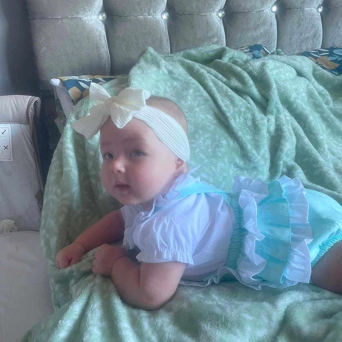 Jersey-Rose joined the competition — help win amazing prizes! baby, bed, bedroom, blanket, blue, bow, child, clothing, cozy, curious, cute, headband, indoors, infant, lying_down, person, portrait, soft_texture, tufted_headboard, white