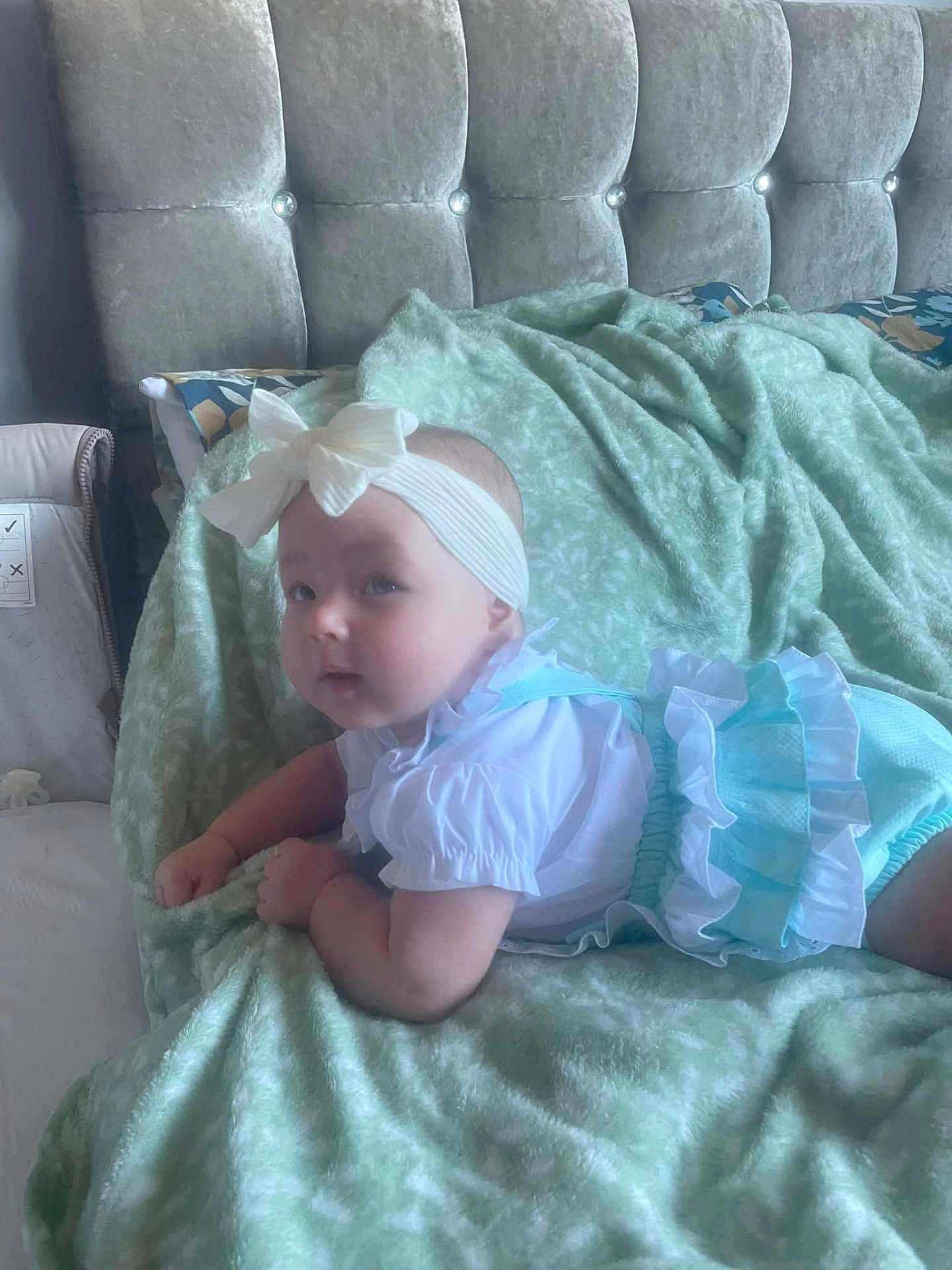 Jersey-Rose joined the competition — help win amazing prizes! baby, bed, bedroom, blanket, blue, bow, child, clothing, cozy, curious, cute, headband, indoors, infant, lying_down, person, portrait, soft_texture, tufted_headboard, white