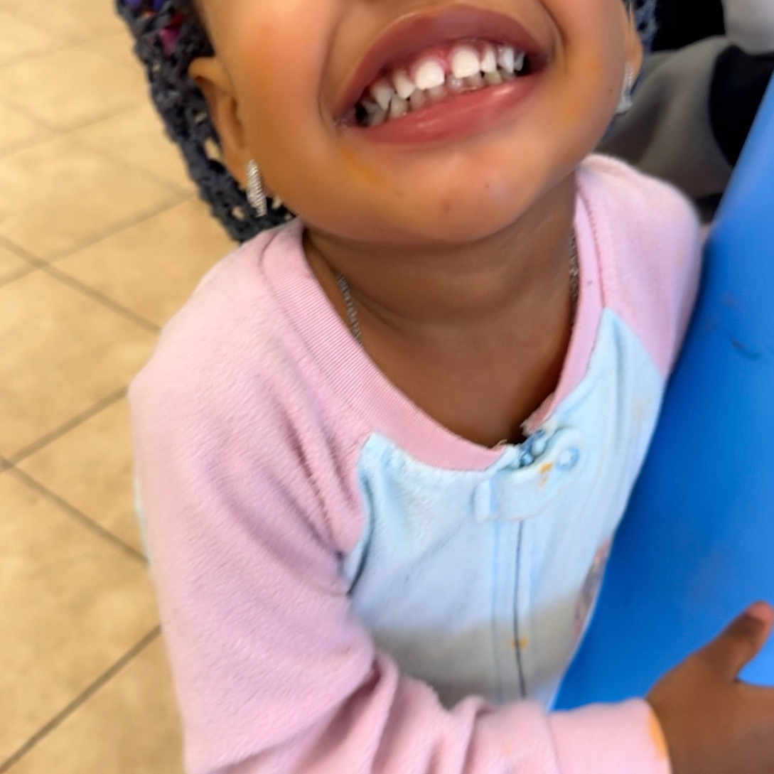 Malaysia is registered to the contest to win money with this photo: beads, blue_pole, braided_hair, casual_wear, child, closeup, cute, earrings, full_body, happy, indoor, jewelry, person, pink_clothing, playful, portrait, smiling, tile_floor, toddler, young