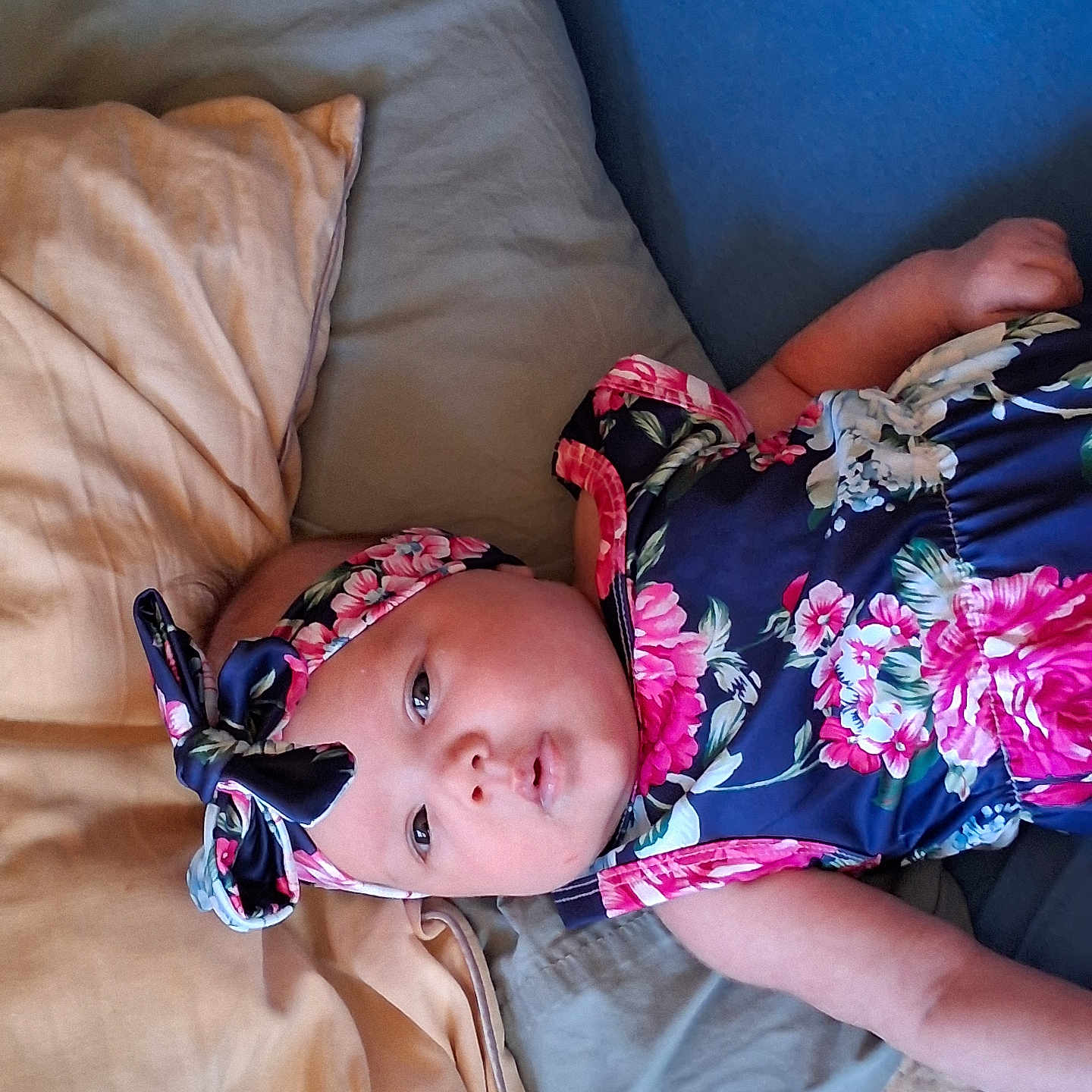 Cecilia is registered to the contest to win money with this photo: baby, infant, bed, pillow, blanket, headband, floral_pattern, clothing, face, skin, arm, lying_down, indoors, cute, portrait, child, sleepwear, comfort, rest, young