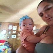 Lexi is registered to the contest to win money with this photo: baby, woman, indoor, blurry, headband, holding, person, portrait, clothing, wood_panel_wall, picture_frames, furniture, casual, child, family, home, people, infant, colorful, room