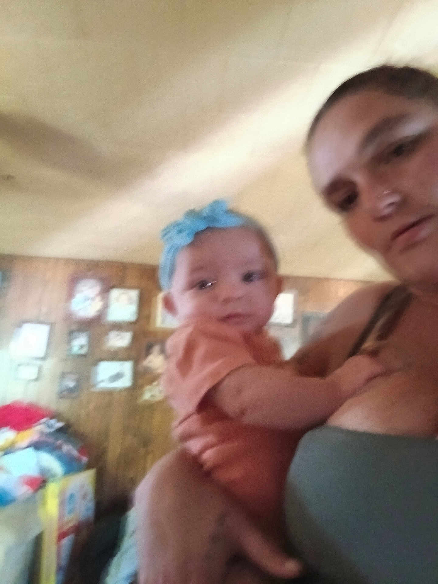 Lexi is registered to the contest to win money with this photo: baby, woman, indoor, blurry, headband, holding, person, portrait, clothing, wood_panel_wall, picture_frames, furniture, casual, child, family, home, people, infant, colorful, room