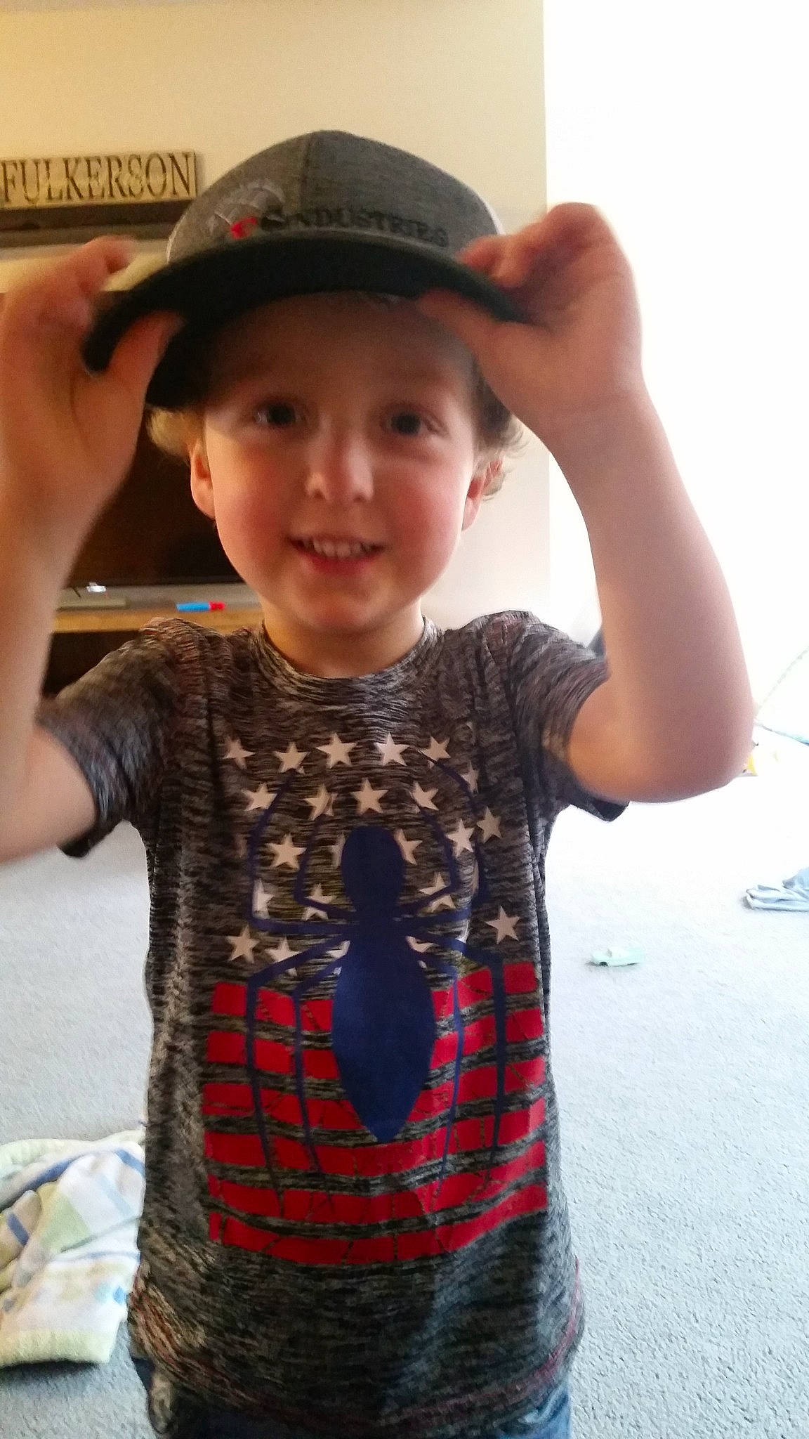 Grayson is registered to the contest to win money with this photo: child, clothing, cool, cowboy_hat, design, fashion_accessory, finger, hand, hat, headgear, headwear, joy, pattern, person, plaid, smile, sun_hat, t_shirt, tartan, toddler