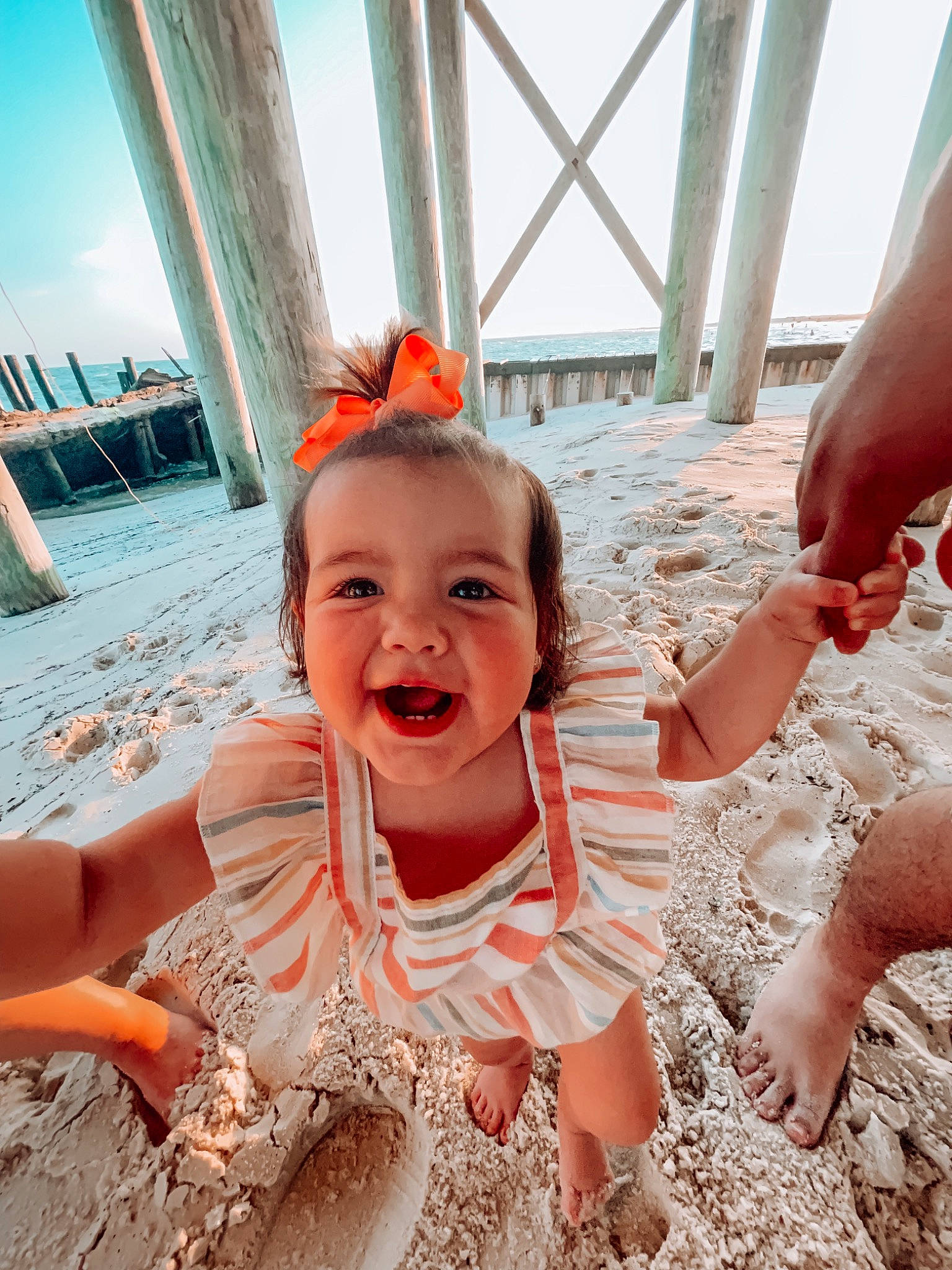 Amelia Rose joined the competition — help win amazing prizes! beach, child, dress, event, fashion_accessory, finger, fun, gesture, happy, leisure, orange, people_in_nature, people_on_beach, person, sand, sitting, sky, smile, sunlight, toddler