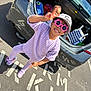 bag, car, casual, child, children, clothing, happy, hat, outdoor, parking_lot, peace_sign, person, playful, purple_outfit, smile, sneakers, sunglasses, sunlight, toy, trunk