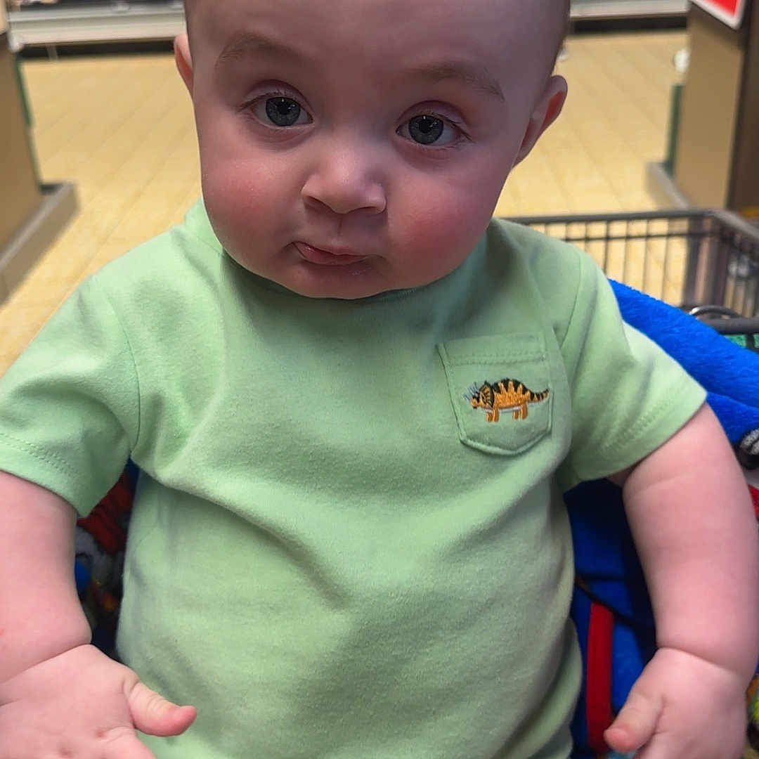 Oliver is registered to the contest to win money with this photo: baby, bodypart, clothing, face, finger, food, grocerystore, hand, head, indoors, market, person, photography, portrait, shelf, shop, shopping, shoppingcart, sweets, t_shirt