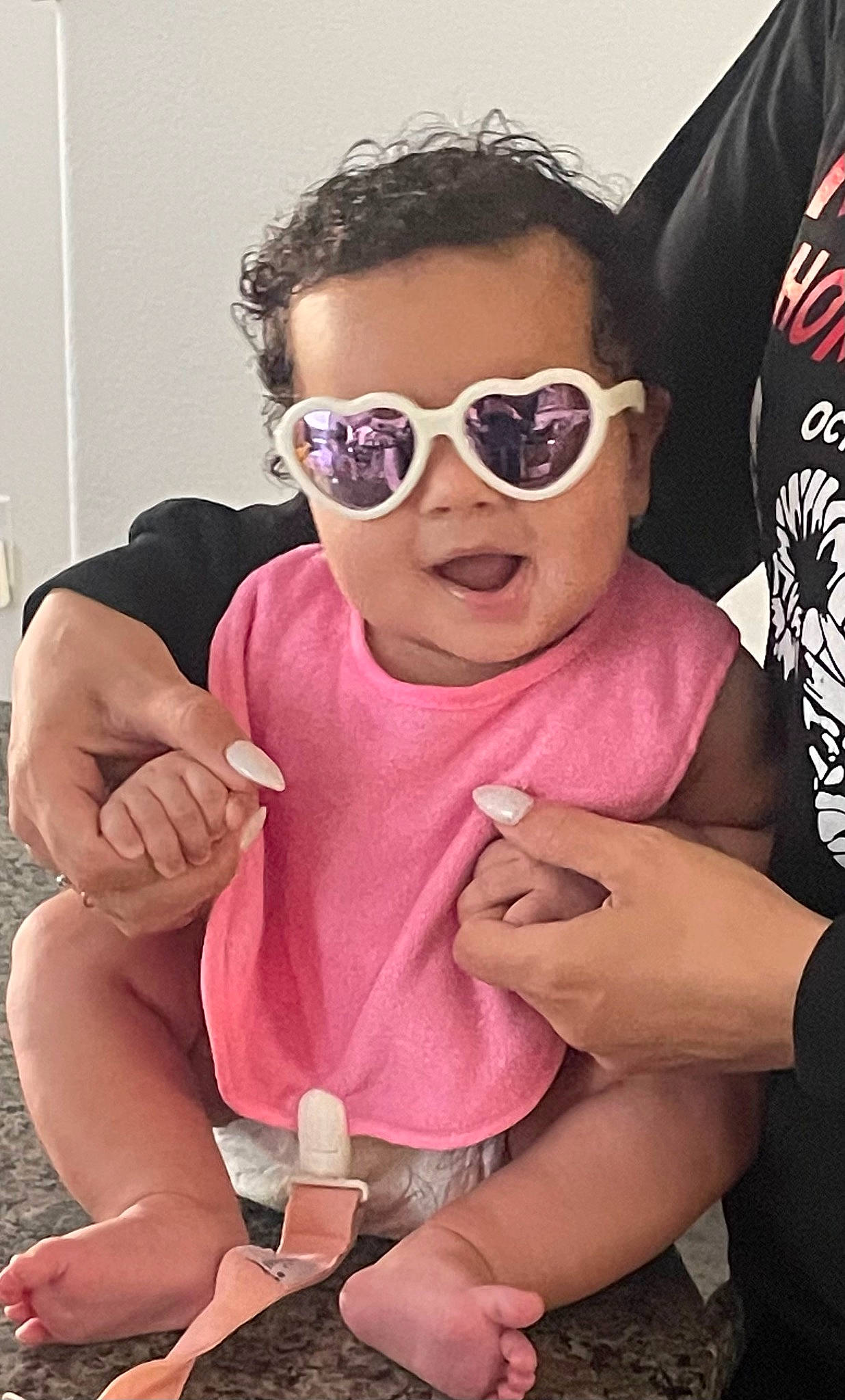 Kaia is registered to the contest to win money with this photo: baby_toddler_clothing, cool, eyewear, finger, gesture, glasses, goggles, hand, happy, lip, magenta, nail, person, personal_protective_equipment, pink, sleeve, sunglasses, thigh, thumb, toddler