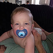 Tim joined the competition — help win amazing prizes! adult_hand, baby, bare_skin, blue_eyes, brown_hair, child, close_up, couch, facial_expression, family, home, indoor, infant, kitchen, lying_down, pacifier, photography, portrait, sitting, stitch