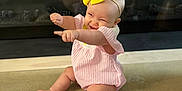 Gwendolyn is registered to the contest to win money with this photo: baby, celebration, cheerful, child, cute, decorative_flags, floor, fun, happy, headband, indoor, infant, pink_outfit, playful, pointing, portrait, sitting, smiling, yellow_bow, young_child