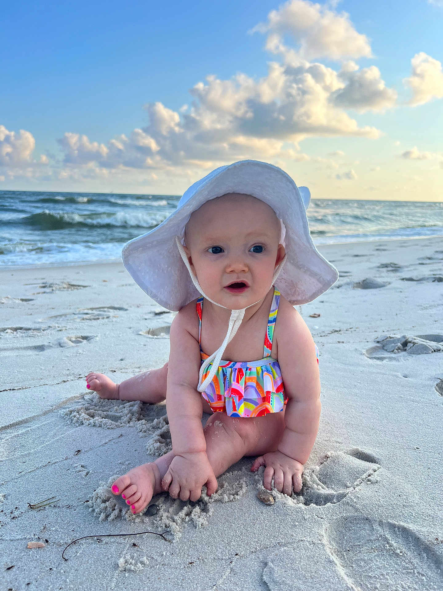 Gwendolyn joined the competition — help win amazing prizes! baby, child, beach, sand, ocean, water, waves, sky, clouds, sunhat, swimsuit, barefoot, footprints, summer, vacation, outdoor, cute, sitting, playing, nature
