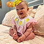 baby, bedspread, child, cozy, cross_legged, cute, decor, furniture, happy, headband, indoors, infant, person, pink_clothing, portrait, sitting, smile, soft_lighting, texture, yellow_bow