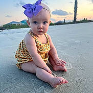 Gwendolyn joined the competition — help win amazing prizes! baby, beach, bow, child, clothing, clouds, cute, footwear, headband, nature, outdoor, palm_tree, portrait, purple, sand, sitting, sky, sunset, toes, vacation
