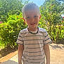 child, boy, smiling, outdoor, sunlight, nature, plants, flowers, necklace, tshirt, casual_clothing, portrait, greenery, daytime, happy, standing, person, young, cute, garden