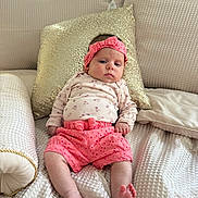 Galilea joined the competition — help win amazing prizes! baby, infant, bed, pillow, pink_clothing, headband, soft_fabric, texture, indoor, person, child, cute, relaxed, portrait, seated, comfortable, floral_pattern, home, cozy, pink_shorts