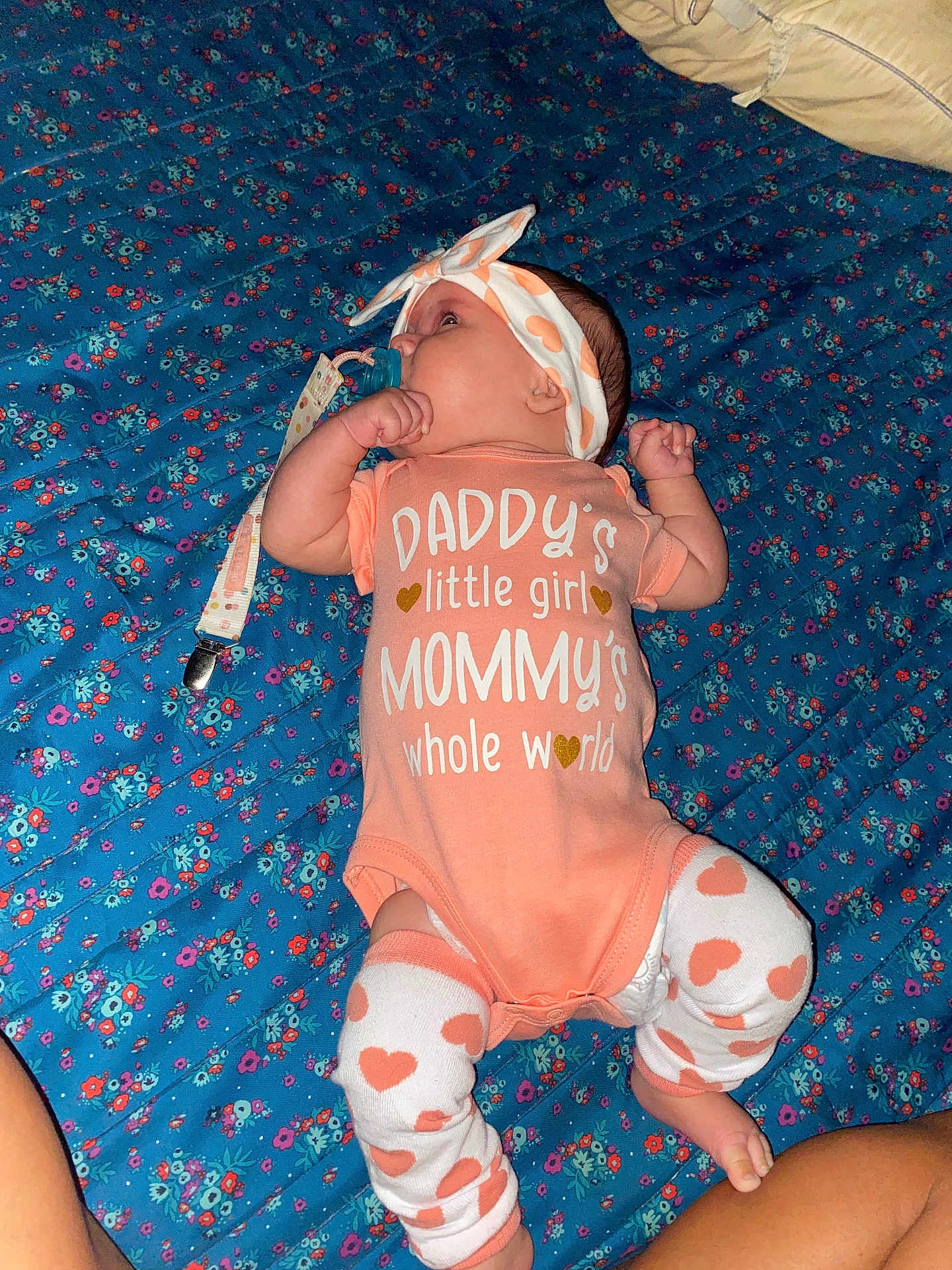 Hailey is registered to the contest to win money with this photo: baby, infant, girl, onesie, headband, pacifier, blanket, blue, floral, pattern, clothing, lying, cute, child, toddler, socks, legs, cute_outfit, closeup, indoors