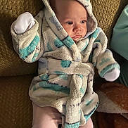 Hailey is registered to the contest to win money with this photo: baby, child, robe, hood, mittens, couch, blanket, pink_pants, soft_fabric, indoor, face, person, young_child, seated, warm_clothing, comfort, relaxed, infant, cozy, portrait