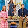 child, adult, group, stage, school_event, smiling, dress, microphone, backdrop, laptop, chair, boots, tie, lanyard, happy, indoor, people, presentation, decorations, event