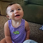Estella is registered to the contest to win money with this photo: baby, child, smiling, purple_clothing, sitting, carpet, indoor, couch, turtle_patch, happy, toddler, person, face, cute, young_child, home, casual, infant, bright_eyes, polka_dot