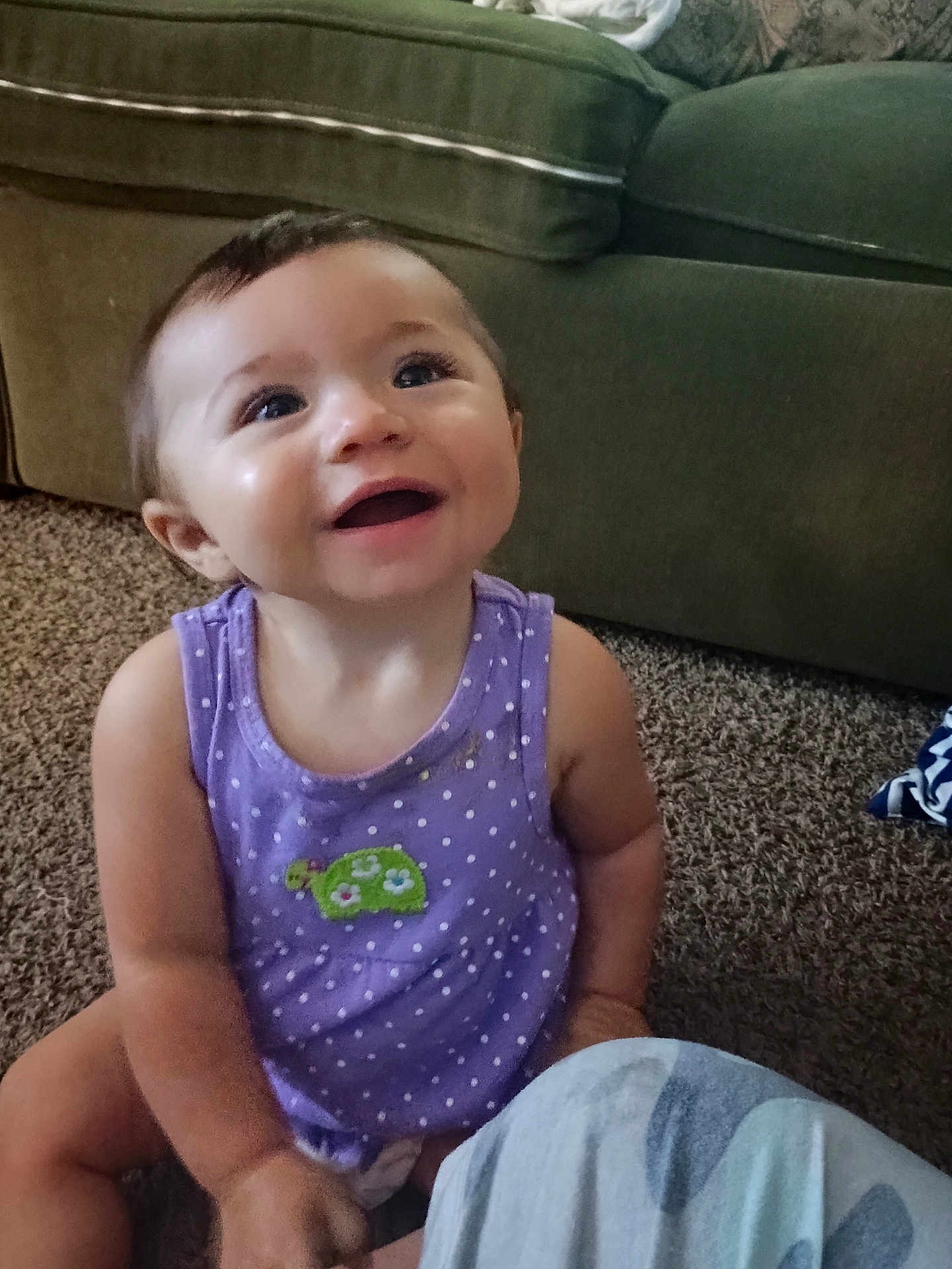 Estella is registered to the contest to win money with this photo: baby, child, smiling, purple_clothing, sitting, carpet, indoor, couch, turtle_patch, happy, toddler, person, face, cute, young_child, home, casual, infant, bright_eyes, polka_dot
