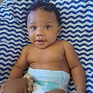 Amri joined the competition — help win amazing prizes! baby, child, infant, diaper, wavy_blanket, blue_and_white_pattern, striped_pattern, curly_hair, smiling, wide_eyes, torso, arm, hand, pacifier_clip, wooden_beads, lying_down, indoor, closeup, portrait, skin_tone