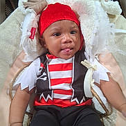 Amri is registered to the contest to win money with this photo: baby, infant, child, portrait, lying_down, red_hat, costume, striped_shirt, pirate_costume, blanket, stuffed_animal, fluffy, cuddly, tongue, wide_eyes, indoors, baby_photography, sitting, playful, close_up