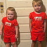 Payslee joined the competition — help win amazing prizes! child, children, red_clothing, shorts, tshirt, door, indoor, footwear, expression, standing, matching_outfits, person, cute, serious_face, wood_floor, wall, hair, smile, portrait, siblings