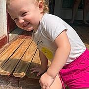Payslee is registered to the contest to win money with this photo: toddler, child, smiling, curly_hair, white_shirt, pink_shorts, sunlight, outdoor, wooden_porch, shadow, barefoot, person, playful, candid, happy, sunny, portrait, daylight, casual, fun