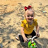 Payslee is registered to the contest to win money with this photo: toddler, child, red_bow, yellow_shirt, toy_scooter, outdoor, sunlight, dirt_path, shadows, smiling, play, sandals, curly_hair, happy, cute, green_toy, summer, fun, person, casual