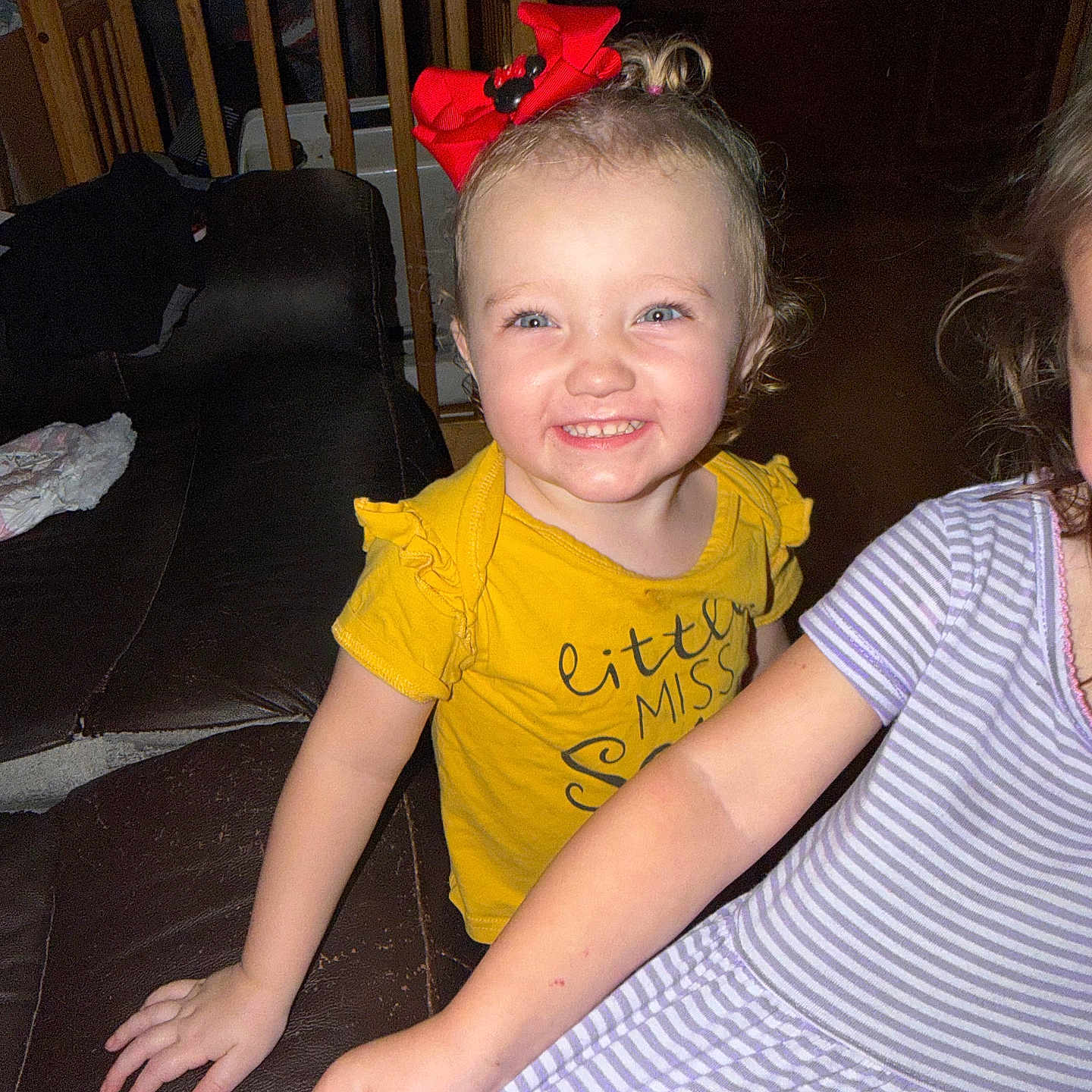 Payslee joined the competition — help win amazing prizes! toddler, child, smile, red_bow, yellow_shirt, striped_dress, couch, indoor, furniture, wooden_chair, happy, person, face, hair, arm, clothing, toy, home, casual, portrait
