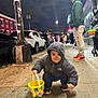 toddler, child, bucket, sidewalk, night, street, people, jacket, hoodie, face_paint, lollipop, cars, man, street_lamp, urban, casual_clothing, sneakers, crowd, city, outdoor