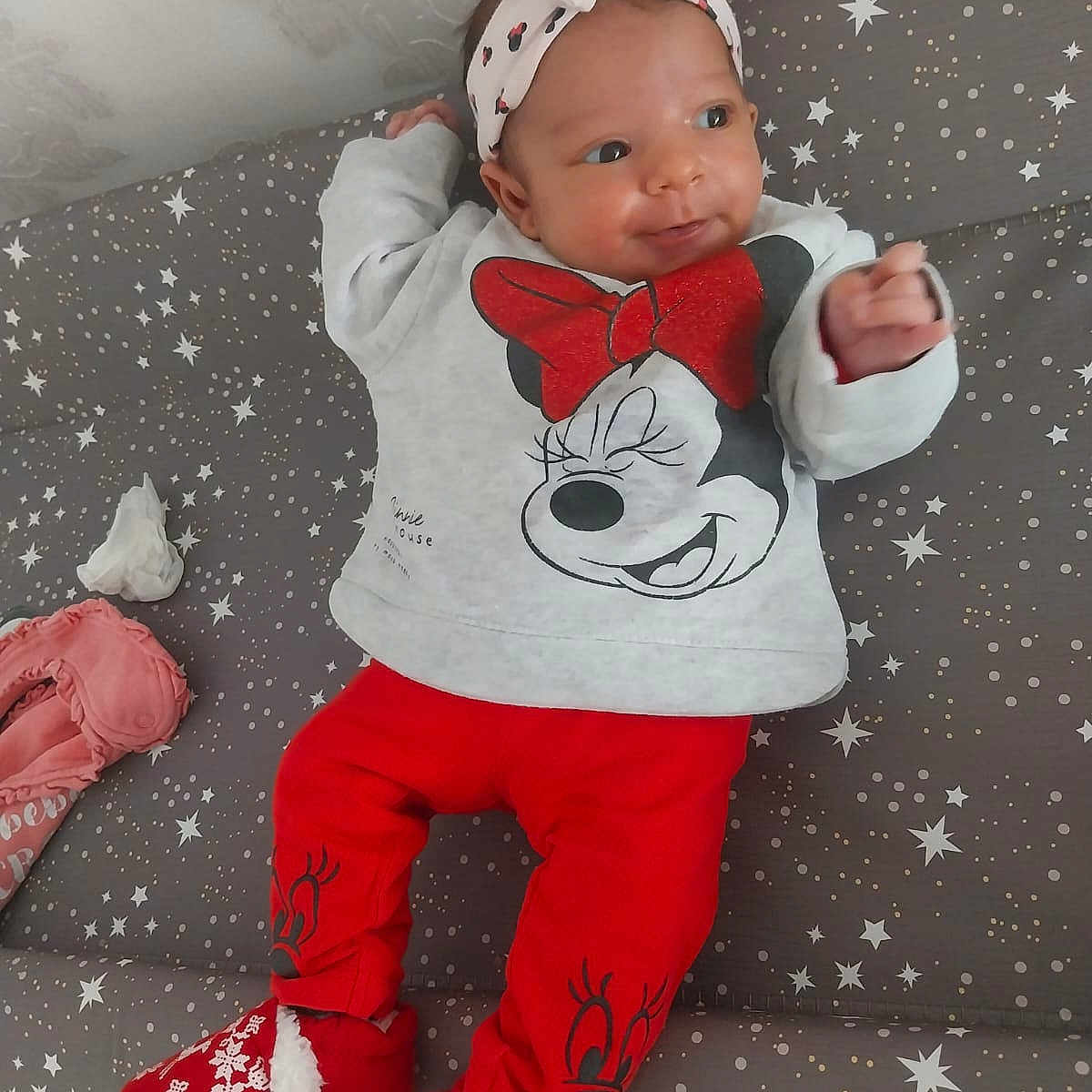 Ralia a rejoint le concours — aidez-le/la à gagner de superbes lots ! apparel, baby, blanket, child, clothing, cozy, cute, face, headband, indoor, infant, lying_down, minnie_mouse, patterned_background, person, red_pants, red_slippers, smiling, soft_toys, stars