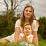 child, baby, girl, outdoor, nature, grass, white_dress, portrait, smile, happy, sitting, young, family, greenery, tree, sky, earrings, hairclip, clothing, photography