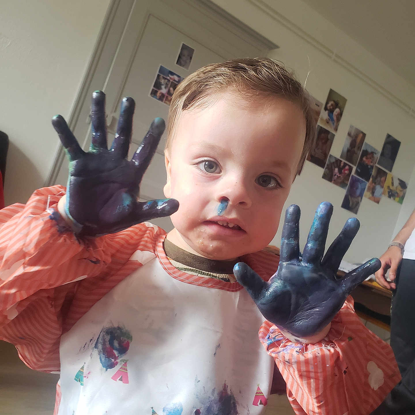 Gabryell participe au concours pour gagner de l'argent avec cette photo : child, clothing, curly_hair, cute, expression, face, floor, hand, home, indoor, messy, paint, paint_on_face, paint_on_hands, person, photography, playful, smock, toddler, wall_photos