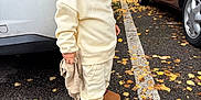 Roméo participe au concours pour gagner de l'argent avec cette photo : toddler, child, parking_lot, autumn, leaves, car, white_car, red_car, hat, knit_hat, sweatshirt, pants, boots, asphalt, toy, curious, outdoor, side_view, fall, street