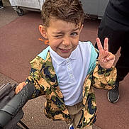 Hugo participe au concours pour gagner de l'argent avec cette photo : boy, casual_clothing, child, dinosaur_pattern, dumpster, hair, hand_gesture, jacket, outdoor, pavement, peace_sign, person, playful, smile, sneakers, standing, stroller, urban, winking, young