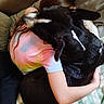 Rocky a rejoint le concours — aidez-le/la à gagner de superbes lots ! dog, person, hugging, couch, blanket, tie_dye_shirt, black_dog, white_markings, indoor, comfort, affection, pet, animal, human, friendship, relaxation, close_up, cozy, resting, bond