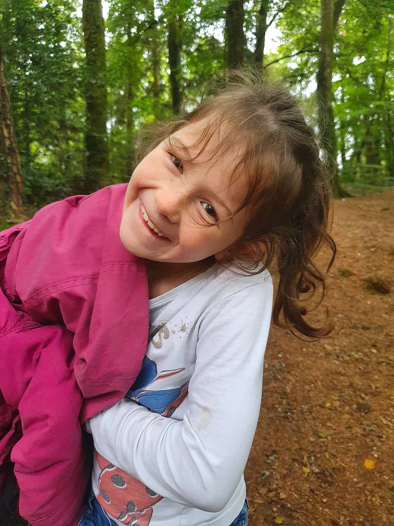 Cynthia a rejoint le concours — aidez-le/la à gagner de superbes lots ! blond, brown_hair, forest, fun, grass, happy, joy, jungle, leaf, leisure, people_in_nature, person, plant, recreation, sitting, smile, soil, toddler, tree, trunk